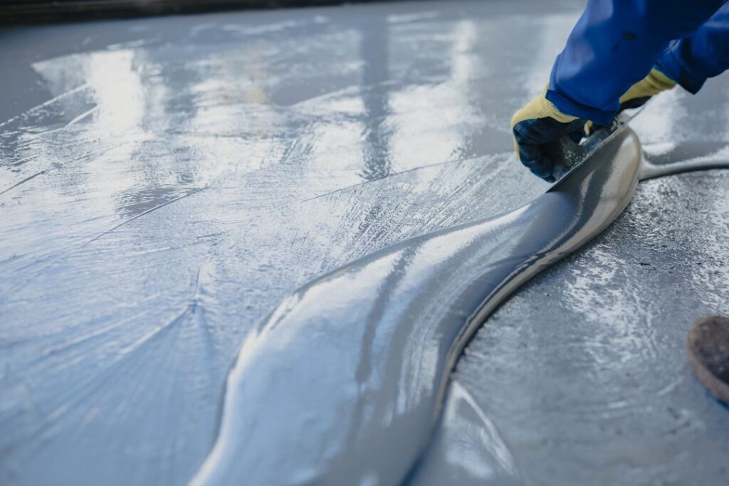 Concreter pours epoxy coating on concrete